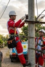 Petugas PLN memperbaiki jaringan listrik di kampung Indonesia untuk pemeliharaan rutin.