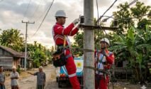 Petugas PLN memperbaiki jaringan listrik di kampung Indonesia untuk pemeliharaan rutin.