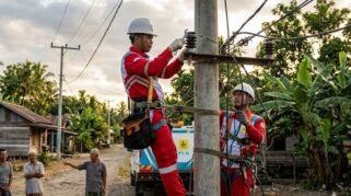 Petugas PLN memperbaiki jaringan listrik di kampung Indonesia untuk pemeliharaan rutin.