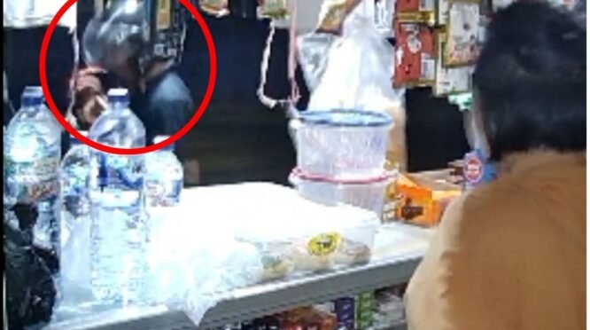 Cuplikan video rekaman CCTV yang terbagi dua layar atas dan bawah, memperlihatkan kondisi bagian dalam sebuah kios sembako yang berantakan dengan etalase kaca berisi barang dagangan. Tampak beberapa orang di dalam area toko dalam situasi yang tidak kondusif dan menegangkan.
