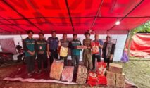 Dokumentasi penyerahan bantuan logistik kemanusiaan di posko Dinas Sosial Bone. Terlihat tim LAZ WIZ dan petugas Dinas Sosial sedang memilah dan menumpuk barang bantuan. Aset logistik yang terlihat jelas di antaranya tumpukan rak telur ayam di dalam wadah plastik, beberapa karung beras premium (merek 788 terlihat pada karung), dan kotak-kotak karton berisi mi instan. Di latar belakang terdapat aktivitas posko dan spanduk informasi yang agak buram. Pencahayaan alami siang hari.