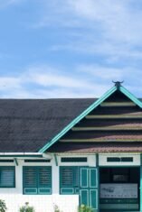 Fasad depan bangunan Museum La Pawawoi Bone dengan arsitektur tradisional atap pelana bertumpuk dan ornamen kepala kerbau di puncaknya, di bawah langit biru berawan.