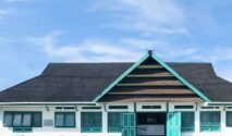 Fasad depan bangunan Museum La Pawawoi Bone dengan arsitektur tradisional atap pelana bertumpuk dan ornamen kepala kerbau di puncaknya, di bawah langit biru berawan.