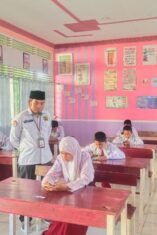 Suasana pelaksanaan Asesmen Madrasah perdana yang menggunakan perangkat smartphone di ruang kelas MIN 5 Bone. Turut terlihat guru pengawas memantau kelancaran ujian.