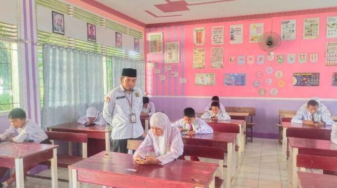 Suasana pelaksanaan Asesmen Madrasah perdana yang menggunakan perangkat smartphone di ruang kelas MIN 5 Bone. Turut terlihat guru pengawas memantau kelancaran ujian.