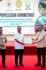 Sesi foto bersama di panggung Aula Asta Cita berlatar layar digital besar bertuliskan "PENYELESAIAN ADMINISTRASI BANTUAN KEMASYARAKATAN (BANMAS) PRESIDEN BERUPA SAPI". Lima orang pria berdiri berjejer mengenakan pakaian batik dan kemeja rapi, di mana dua orang di antaranya yang berada di tengah sedang memegang map dokumen serah terima sapi kurban bantuan Presiden.