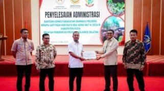 Sesi foto bersama di panggung Aula Asta Cita berlatar layar digital besar bertuliskan "PENYELESAIAN ADMINISTRASI BANTUAN KEMASYARAKATAN (BANMAS) PRESIDEN BERUPA SAPI". Lima orang pria berdiri berjejer mengenakan pakaian batik dan kemeja rapi, di mana dua orang di antaranya yang berada di tengah sedang memegang map dokumen serah terima sapi kurban bantuan Presiden.