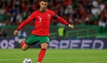 Cristiano Ronaldo bersiap menendang bola di tengah lapangan saat mengenakan seragam Timnas Portugal.