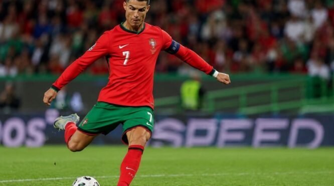 Cristiano Ronaldo bersiap menendang bola di tengah lapangan saat mengenakan seragam Timnas Portugal.