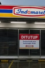 Gerai Indomaret tutup dengan pintu tertutup dan papan pemberitahuan ditutup di bagian depan toko.