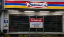 Gerai Indomaret tutup dengan pintu tertutup dan papan pemberitahuan ditutup di bagian depan toko.