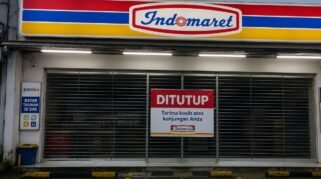 Gerai Indomaret tutup dengan pintu tertutup dan papan pemberitahuan ditutup di bagian depan toko.