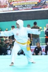 Dua pesilat anak berhadapan di arena pencak silat dengan seorang wasit di tengah pertandingan Arung Palakka Championship I Piala Bupati Bone 2026.