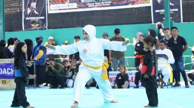 Dua pesilat anak berhadapan di arena pencak silat dengan seorang wasit di tengah pertandingan Arung Palakka Championship I Piala Bupati Bone 2026.