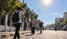 Ilustrasi warga berjalan kaki di jalan beraspal saat cuaca terik, menggambarkan kondisi potensi udara panas di Bone.