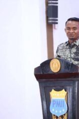 Bupati Bone menyampaikan sambutan di podium berlambang PMII dalam kegiatan Sekolah Kader KOPRI ke-III Se-Indonesia Timur.