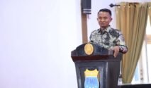 Bupati Bone menyampaikan sambutan di podium berlambang PMII dalam kegiatan Sekolah Kader KOPRI ke-III Se-Indonesia Timur.