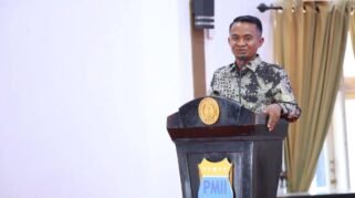 Bupati Bone menyampaikan sambutan di podium berlambang PMII dalam kegiatan Sekolah Kader KOPRI ke-III Se-Indonesia Timur.